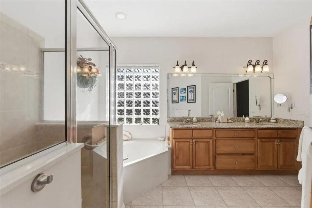 Primary bathroom with glass shower, soaking tub, and double granite vanity