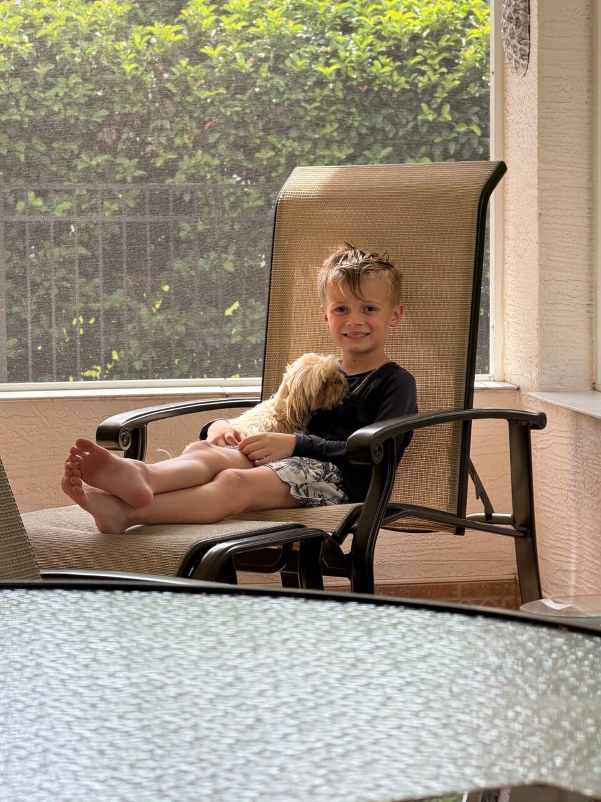 Young guest relaxing on the screened lanai at The Heart of Palms with a small dog curled up beside him
